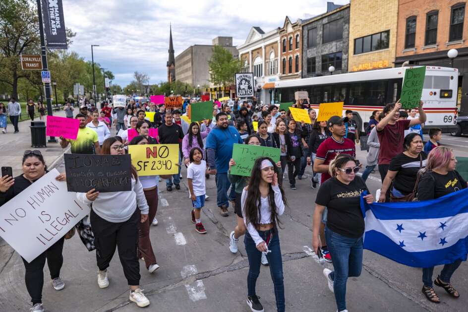 Protesters on Wednesday make their way down Clinton Street in Iowa City.  Nonprofit Escucha Mi Voz led a “Rally for Human Dignity” calling for an end to Senate File 2340, a new state immigration law that is also being challenged by the federal government.  (Geoff Stellfox/The Gazette)