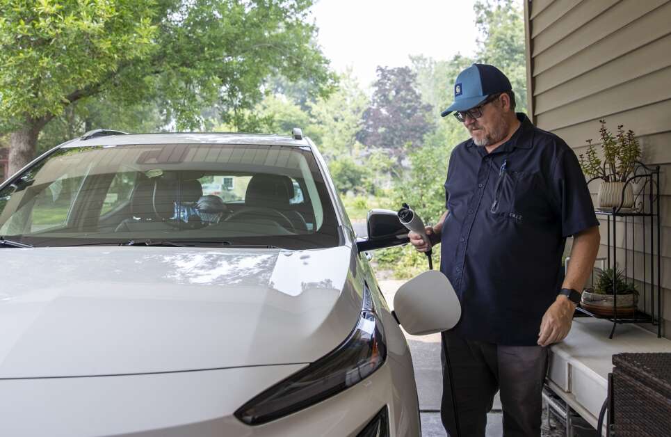 Mike Carberry of Iowa City plugs in his electric vehicle to his charger Tuesday at his home in Iowa City. Carberry says he typically uses fast charging stations like one at the Iowa River Landing parking garage to get up to 80 percent of charge in 30 minutes, and will use his home charger overnight to get the last 20 percent. (Savannah Blake/The Gazette)
