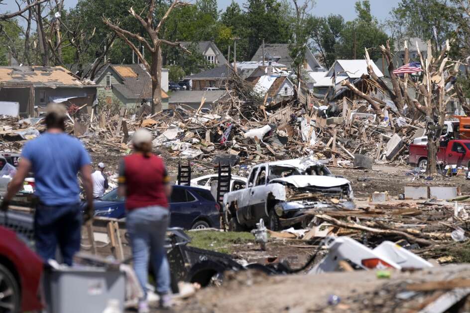 People survey a tornado damaged neighborhood, May 23, in Greenfield, Iowa. (AP Photo/Charlie Neibergall)