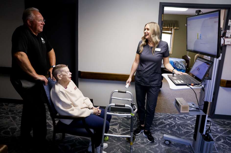 Doctor of Physical Therapy and Director of Rehab Services Amanda Rose (right) shares a laugh with resident Margaret Selzer (center) and administrator Richard Curphey as they demonstrate a gait analysis system at West Ridge Care Center in northwest Cedar Rapids on May 8. The VSTBalance system uses artificial intelligence and machine vision to identify deficits in balance, gait, and function: three indicators of fall risk. The analysis helps Rose tailor a care plan to strengthen balance, gait, and function. (Jim Slosiarek/The Gazette)