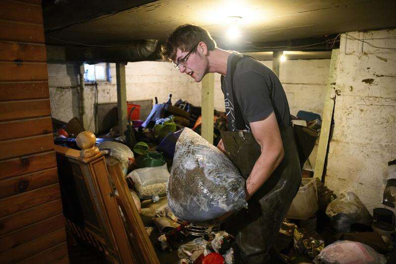 Volunteer Tyron Berkenpas, an employee of Maintenance Corporation in Sheldon, removes a bag of flood-damaged items from the basement of a home in Spencer on Tuesday.  Spencer, with a population of about 11,400, is recovering after the Little Sioux River flooded much of the city last weekend.  Authorities say the flooding affected about 40 percent of properties in the city.  (Tim Hynds/Sioux City Journal via AP)