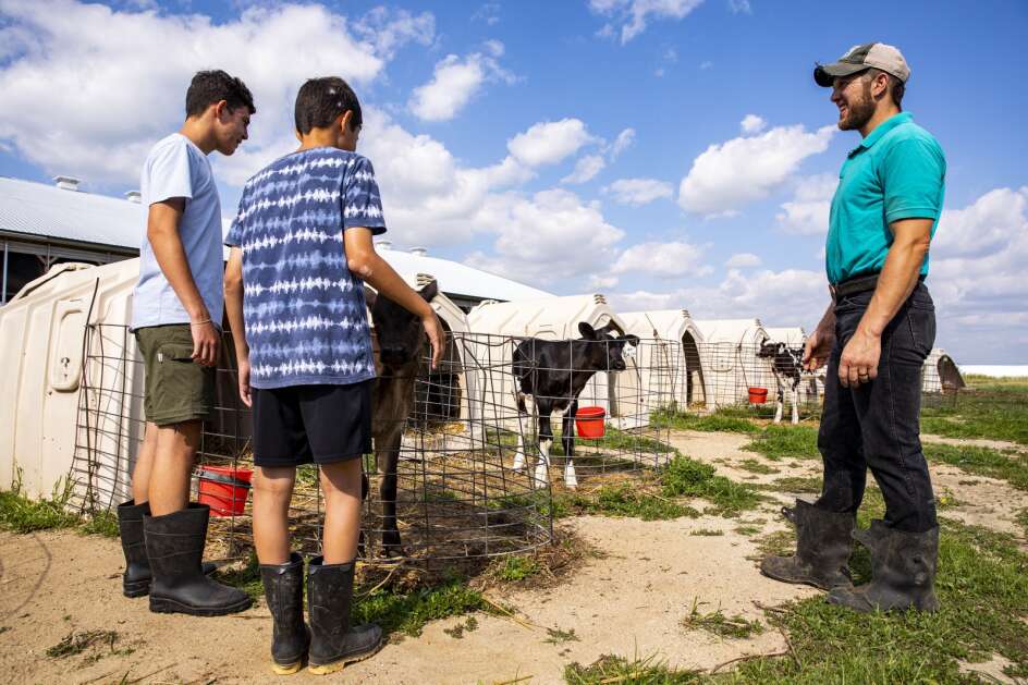 Dan Bolin (right) talks with Ian Eason, 14, and Aric Eason, 12,  on Aug. 17 at the Bolin family’s New Day Dairy in Clarksville. The Easons and their parents spent a week at the farm’s bed-and-breakfast, learning about farming and helping with farm tasks. The Bolin operation was cited by the state Department of Agriculture for its “modern barn designed with cow comfort in mind.” (Nick Rohlman/The Gazette)