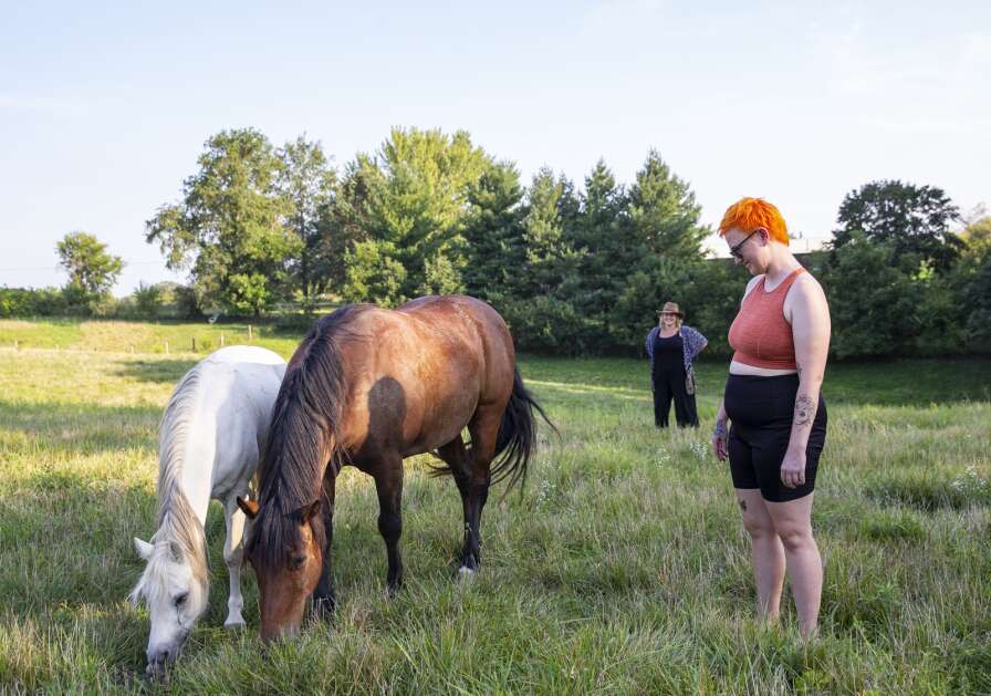 Psychotherapist Natalie Benway-Correll of Iowa City watches the interaction as Rachel Smith of Coralville observes two mares grazing during The Well Lived Life retreat at Lovely Bunches Farm in Iowa City, Iowa on Sunday, Aug. 20, 2023. (Savannah Blake/The Gazette)