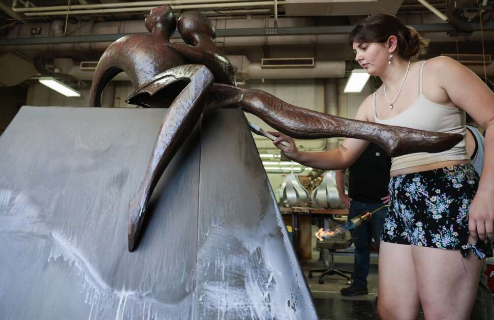 University of Northern Iowa junior Stacia Iverson brushes sculpture wax June 26 onto “Between Friends” as the sculpture undergoes a refurbishment at the Public Art Incubator in the Kamerick Art Building in Cedar Falls. Students in the project refurbish and bring to life art pieces for numerous cities in the state. “Between Friends” is usually displayed in downtown Cedar Rapids. (Jim Slosiarek/The Gazette)