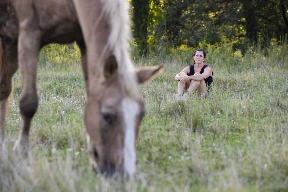 Kara Krapfl of Iowa City observes a horse feeding in a pasture during The Well Lived Life retreat at Lovely Bunches Farm in Iowa City, Iowa on Sunday, August 20, 2023. The retreat is horse-oriented and allows participants to improve their mental health by learning from the behaviors of horses. (Savannah Blake/The Gazette)