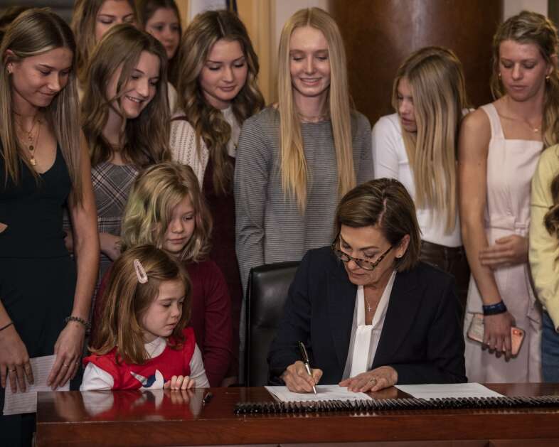 Iowa Governor Kim Reynolds signs House File 2416 at The Iowa State Capitol in Des Moines, Iowa on Thursday, March 3, 2022. The bill, which takes effect immediately, bans transgender girls from participating in girls sports. (Nick Rohlman/The Gazette)