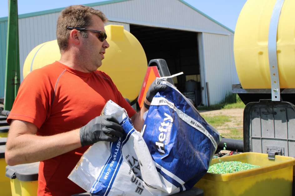 Jason Haglund, a trained addiction counselor and mental health advocate, loads corn kernels into a planter on his family's farm near Boone on May 17. His family has farmed the area for about 140 years, and he is the fifth generation to do the work. (Tony Leys/KFF Health News)