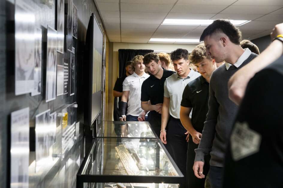 Iowa football players look over items on display during an April 12 ceremony celebrating the opening of a permanent exhibit honoring University of Iowa alum Harold Bradley Jr. at the Iowa Memorial Union. Bradley Jr. was a Hawkeye football player in 1950 and graduated in 1951 with a fine arts degree from the UI. (Nick Rohlman/The Gazette)I
