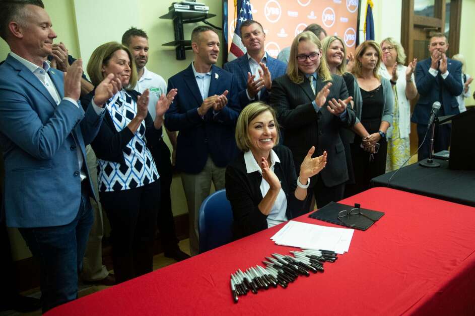 Iowa Gov. Kim Reynolds claps as she signs a sweeping tax cut package that cuts income and property taxes, eliminates the inheritance tax and realigns the state's mental health funding system, on Wednesday, June, 16, 2021, at YSS, in Ames, Iowa.  (Kelsey Kremer/Des Moines Register via AP)