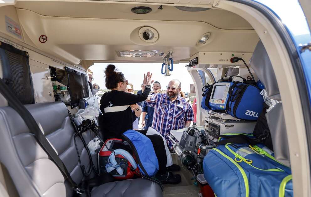 Isabella Sellers (left) gets a high-five from her father, John, after successfully getting into the cabin of an air ambulance Wednesday as she tours a LifeGuard Air Ambulance helicopter at UnityPoint Health-St. Luke’s Hospital in northeast Cedar Rapids. Sellers, of Lithia, Fla., is recovering at the hospital after a fatal, two-vehicle crash Feb. 11 in Black Hawk County. (Jim Slosiarek/The Gazette)
