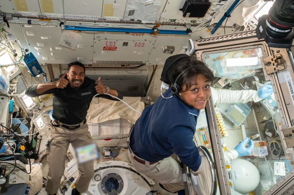 Saudi Space Commission astronauts Ali Alqarni and Rayyanah Barnawi pose for a photo while Barnawi works with a Microgravity Science Glovebox during the Ax-2 mission on May 25, 2023. Barnawi is the first Arab woman in space. (Axiom Space)