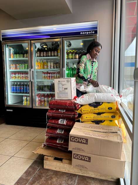 Iphie Basampuka stacks bags of rice in her new store, Sisters’ African Food Market in Cedar Rapids, on May 24, 2022. (Elijah Decious/The Gazette)