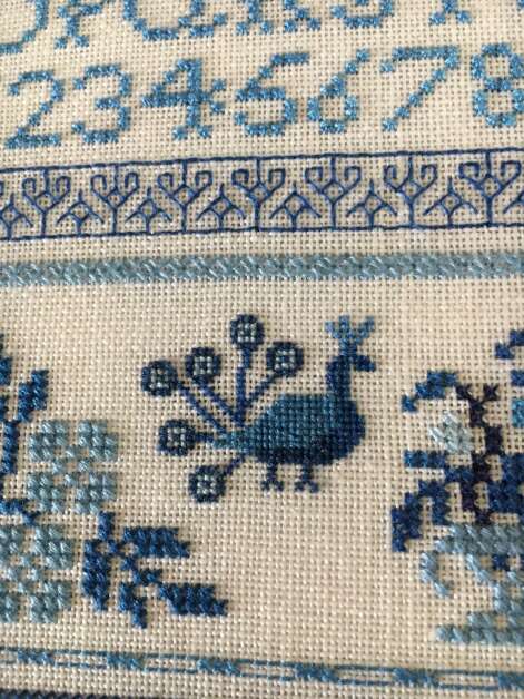 Peacocks are among Sheri Ekstrom's favorites, so the Cedar Rapids needle artist included several on this sampler, done in various shades of blue. (Diana Nollen/The Gazette)