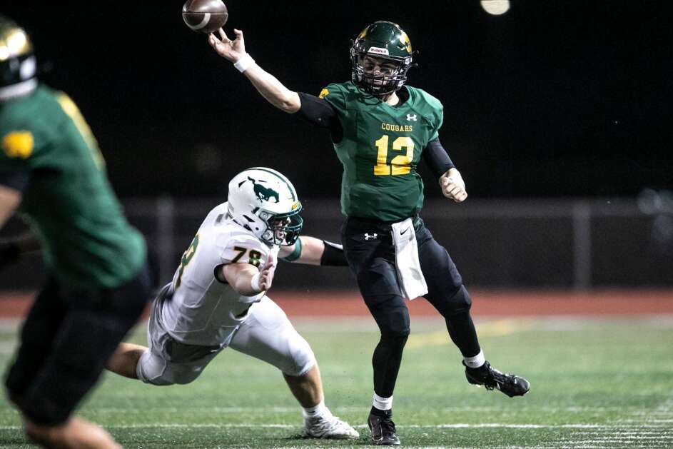 Kennedy quarterback Vincenzo Gianforte (12) escapes a tackle from Hempstead’s Luke Baker (78) during a home football game against Dubuque Hempstead on Thursday, Oct. 5, 2023, Kingston Stadium in Cedar Rapids, Iowa. The Cougars defeated the Mustangs 44-0. (Geoff Stellfox/The Gazette)