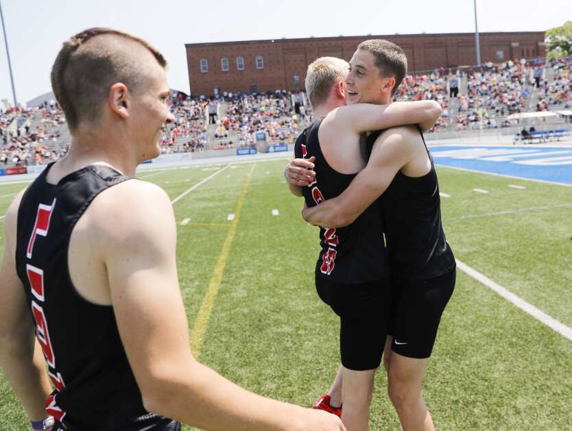 Lisbon's Ben Morningstar (right) hugs Gage Holub (center) as teammate Cohen Kamaus (left) comes in to celebrate the Lions winning the Class 1A boys’ state track and field shuttle hurdle relay Saturday at Drake Stadium in Des Moines. (Jim Slosiarek/The Gazette)