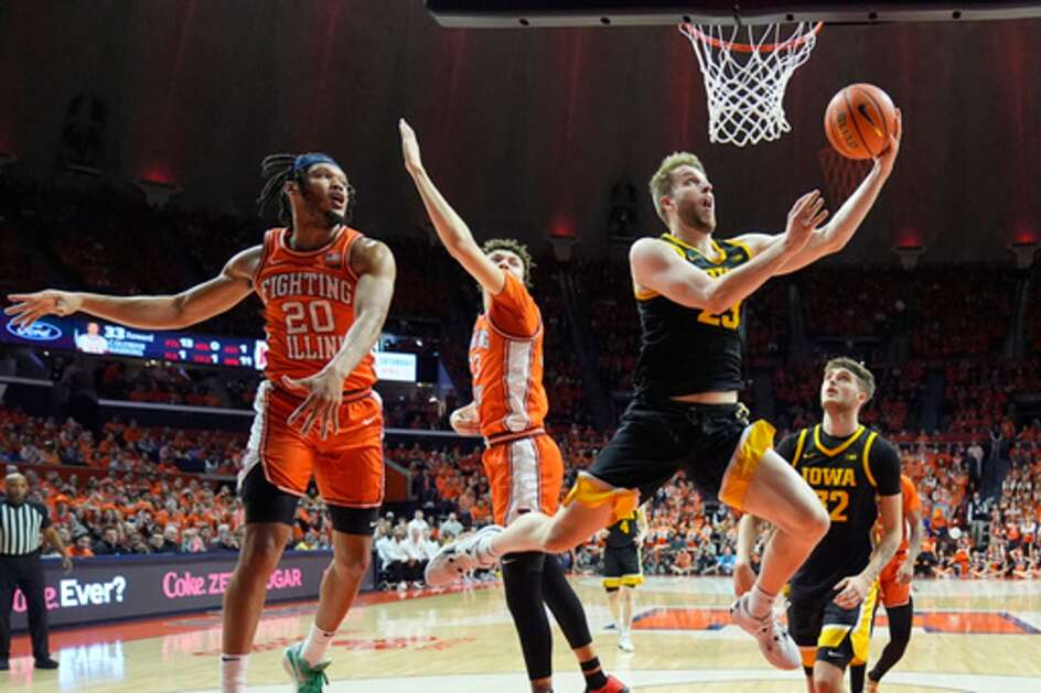 Iowa's Ben Krikke shoots a reverse lay up past Illinois' Ty Rodgers (20) and Coleman Hawkins during the first half of an NCAA college basketball game Saturday, Feb. 24, 2024, in Champaign, Ill. (AP Photo/Charles Rex Arbogast)