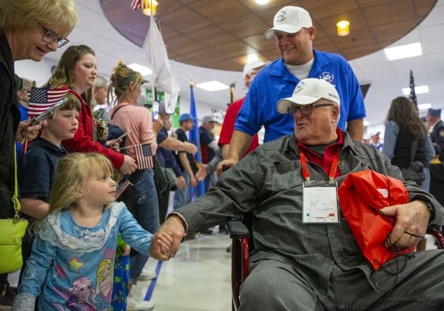 Veteran James Ramsden shakes three-year-old Mitzie Kelley’s hand as he is welcomed back by hundreds of people at the Eastern Iowa Airport in Cedar Rapids, Iowa on Tuesday, April 25, 2023. (Savannah Blake/The Gazette)
