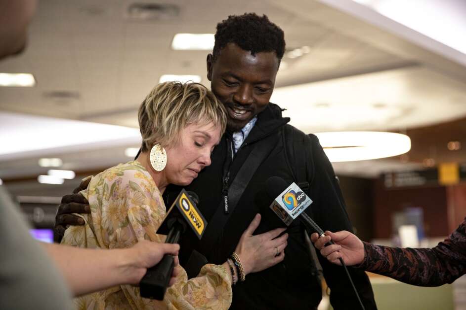 Jacy Bunnell-Ahmed embraces her husband, Mohamed Ahmed, as he is interviewed by news crews, on Tuesday, May 2, 2023, at the Eastern Iowa Airport in Cedar Rapids, Iowa. Ahmed was stranded in Sudan for nearly two weeks as the country’s ongoing civil war damaged the Khartoum airport, preventing flights from leaving the country. After fleeing to Egypt, Ahmed was able to return to the United States. (Geoff Stellfox/The Gazette)