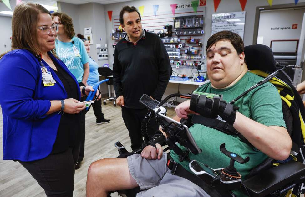 Kyle Spading (right) of Fairfax, on Wednesday explains his combination stylus/medication holder that he developed at the generate lab at UnityPoint Health- St. Luke's Hospital to Jose Gomez-Marquez (center), co-founder of Boston-based MakerHealth, and Nursing Research and Innovation Coordinator Rose Hedges, RN, DNP, during a Maker Faire at the hospital in northeast Cedar Rapids. Spading, a former tight end for the Iowa Hawkeyes, injured his neck and spine in a crash in 2011. The stylus, with conductive material, allows Spading to use his phone and tablet as well as discreetly take medication. (Jim Slosiarek/The Gazette)