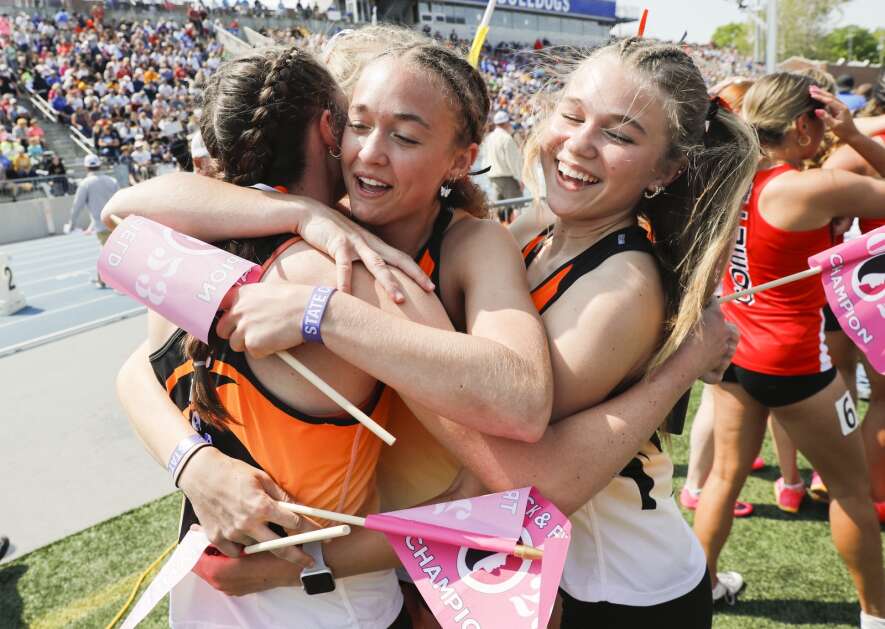 Solon's Mia Stahle (center) hugs Gracie Federspiel (left) as Piper Stahle (right) and Anna Quillin (hidden) celebrate their Class 3A girls’ state track and field distance medley relay win Friday at Drake Stadium in Des Moines. (Jim Slosiarek/The Gazette)