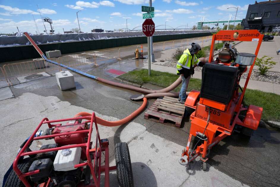 City worker Dylan Estlund monitors pumps near a sand filled flood barrier, Monday, May 1, 2023, in Davenport, Iowa. (AP Photo/Charlie Neibergall)