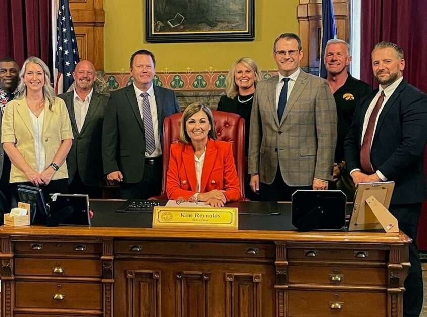 Linn County Attorney Nick Maybanks (at far right) stands with other members of the Iowa County Attorneys Association invited to witness the Thursday signing of a bill by Gov. Kim Reynolds (center) that strengthens prosecution of repeat domestic abuse offenders. (Iowa Governor’s Office) 