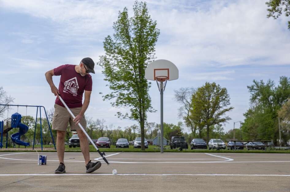 Wells Fargo employee Brian Smith finishes up painting a section of the basketball court at Cedar Valley Park in Cedar Rapids on Thursday while volunteering with his company for Day of Caring. (Savannah Blake/The Gazette)