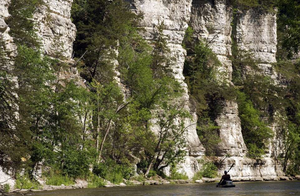 Bill Lewis of Onslow paddles in the shadows near the towering limestone bluffs June 30 along the Upper Iowa River near Bluffton. He was scouting where his extended family could take a night float trip on the Fourth of July weekend. (Jim Slosiarek/The Gazette)