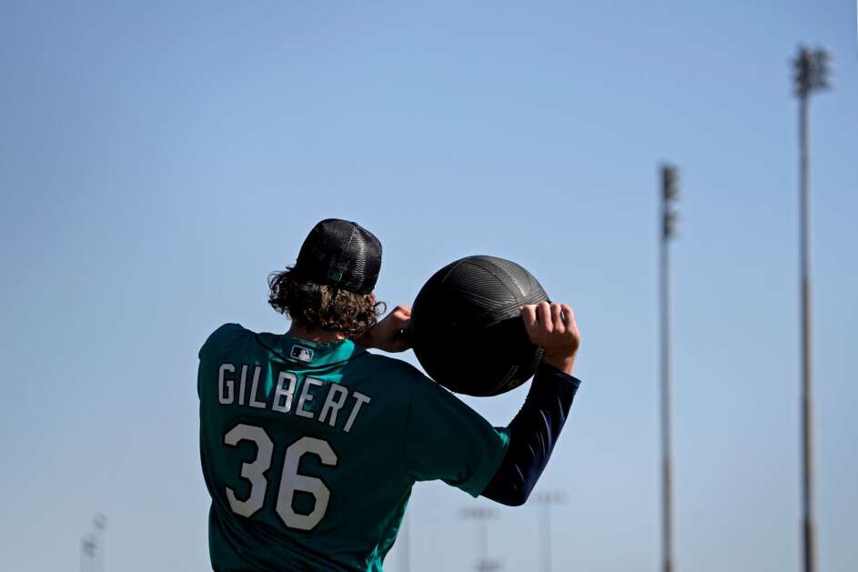 Seattle Mariners pitcher Logan Gilbert works with a medicine ball during spring training baseball practice Thursday, Feb. 16, 2023, in Peoria, Ariz. (AP Photo/Charlie Riedel)
