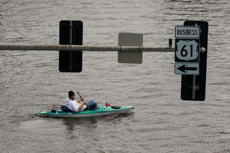 A kayaker floats down a flooded street Monday in downtown Davenport. The Mississippi River crested there Monday, a little bit lower that forecast. (AP Photo/Charlie Neibergall)