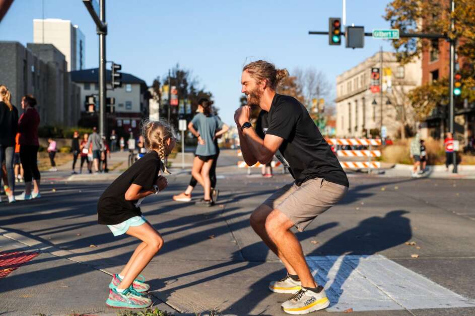 Nick Borchert and his daughter Evelyn, 9, warm up with squats before the 5k race during the Run for the Schools on Sunday, Oct. 23, 2022,  in Iowa City, Iowa. (Geoff Stellfox/The Gazette)