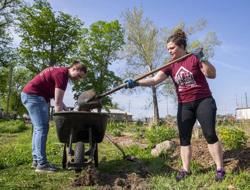 Angel Payne of Aegon Asset Management, left, sorts through dirt to pull out compostable materials as Becky Johnson dumps out a pile of dirt into a wheelbarrow while volunteering for Day of Caring at Cultivate Hope Urban Farm in Cedar Rapids, Iowa on Thursday, May 11, 2023. (Savannah Blake/The Gazette)