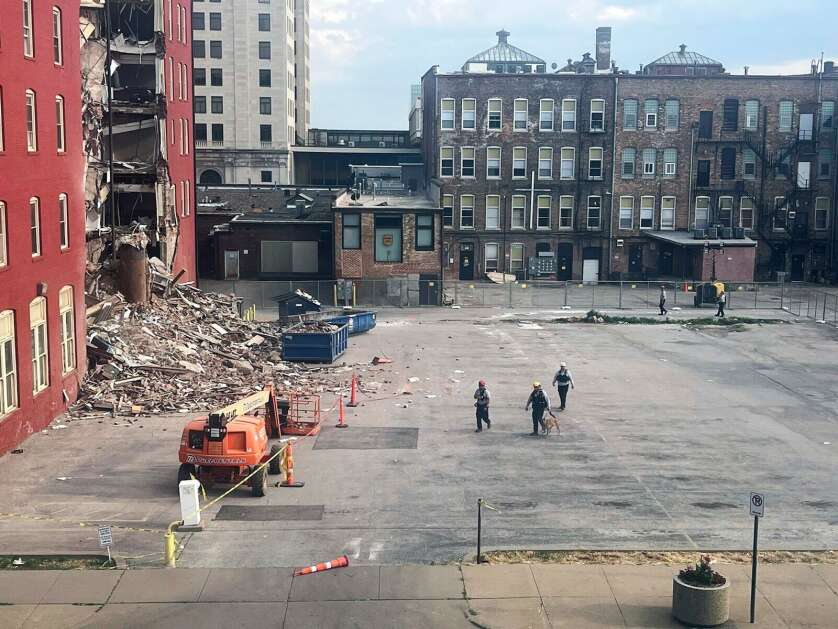 Three search and rescue workers and a dog Thursday approach the site of a building collapse in downtown Davenport. (Grace Kinnicutt/Quad City Times via AP)