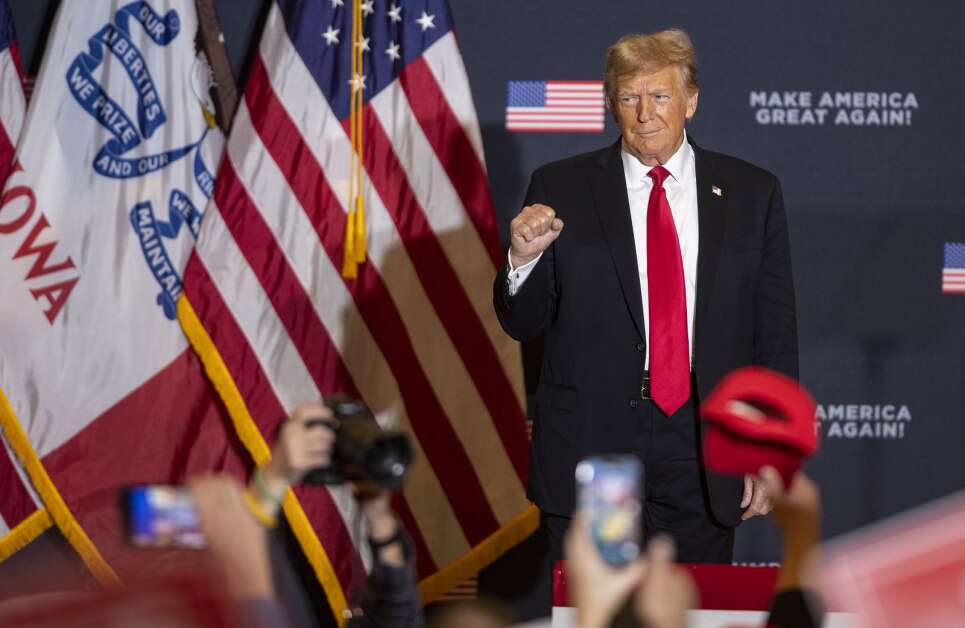 Former President Donald Trump holds a fist up to the to the crowd Dec. 14 as attendees applaud him during a rally at the Hyatt Regency Coralville Hotel. (Savannah Blake/The Gazette)