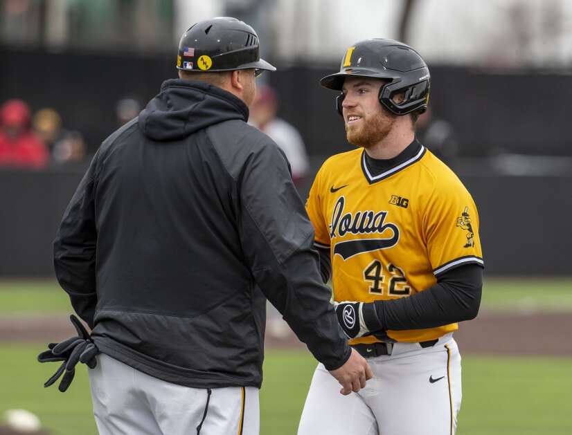 Iowa utility Will Mulflur (42) smiles as he talks with Iowa Assistant Coach David Pearson after getting to walk to first base in the sixth inning of the game against Minnesota at Banks Field in Iowa City, Iowa on Sunday, April 17, 2022.  (Savannah Blake/The Gazette)