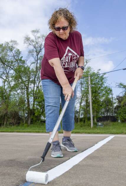 Wells Fargo employee Lois Dougherty paints lines on the basketball court while volunteering with her company for Day of Caring at Cedar Valley Park in Cedar Rapids, Iowa on Thursday, May 11, 2023. (Savannah Blake/The Gazette)