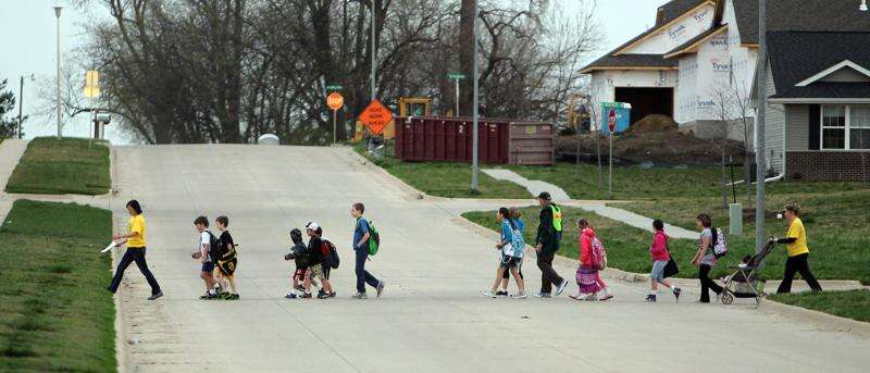 A Walking School Bus driver leads her students across Zeller Street in route to Garner Elementary School in North Liberty. A Walking School Bus (WSB) is a group of children walking together with adult 'drivers' to supervise. (Brian Ray/Gazette Archives)