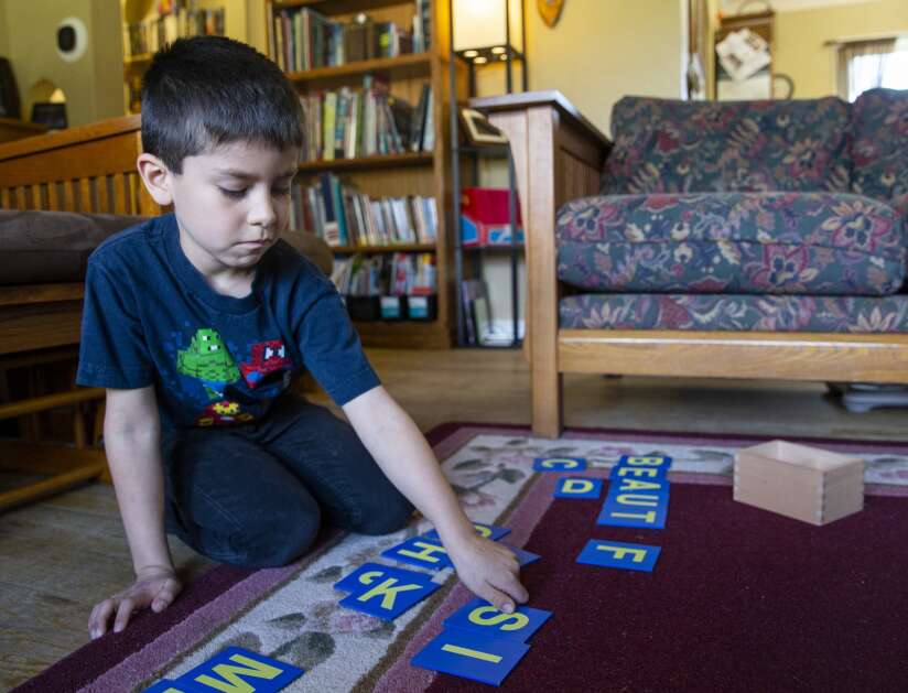 Paul Rustebakke, 7, spells out the word “beautiful” using letter blocks during an April 13 home school lesson with his sister and mother at their home in Cedar Rapids. (Savannah Blake/The Gazette)