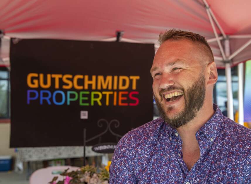 Owner Eric Gutschmidt smiles as he poses for a portrait at the Gutschmidt booth during Pride Fest at NewBo City Market in Cedar Rapids, Iowa on Saturday, July 9, 2022. The houses will be available for rent and will have an open courtyard in the center for neighbors to commune with each other. (Savannah Blake/The Gazette)