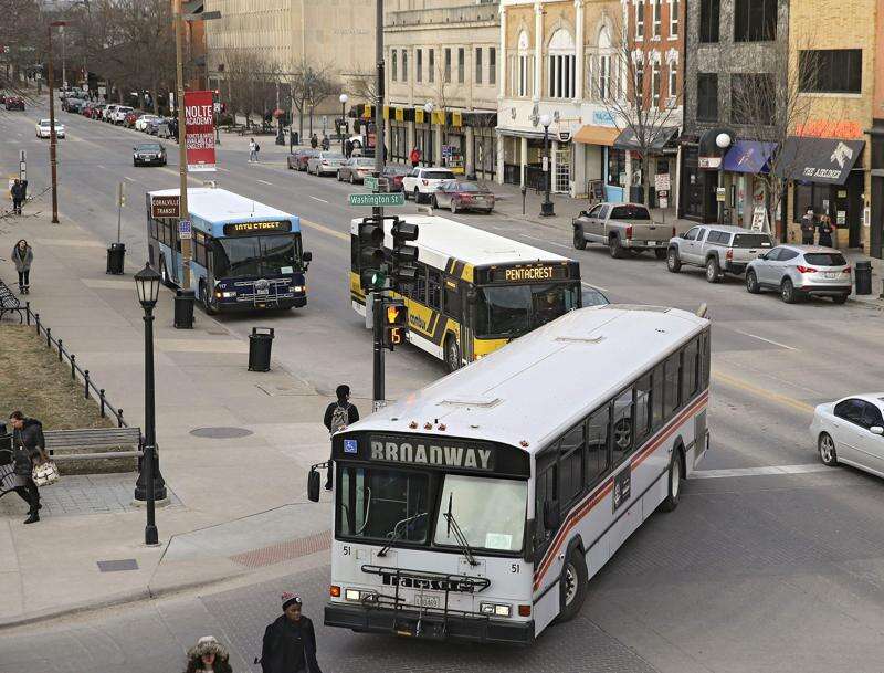 An Iowa City Transit bus (front) turns onto Washington Street while a University of Iowa Cambus (middle) waits behind it and a Coralville Transit bus (back) sits at a stop on Clinton Street in downtown Iowa City in 2018. (The Gazette)