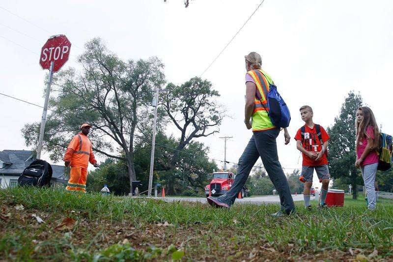 Volunteer Julie McMahan walks waits to cross the street with Jackson Elementary school students Zachary and Margaux Ispentchian on Walk to School Day in NW Cedar Rapids on Wednesday, Oct. 5, 2016. (Adam Wesley/The Gazette)