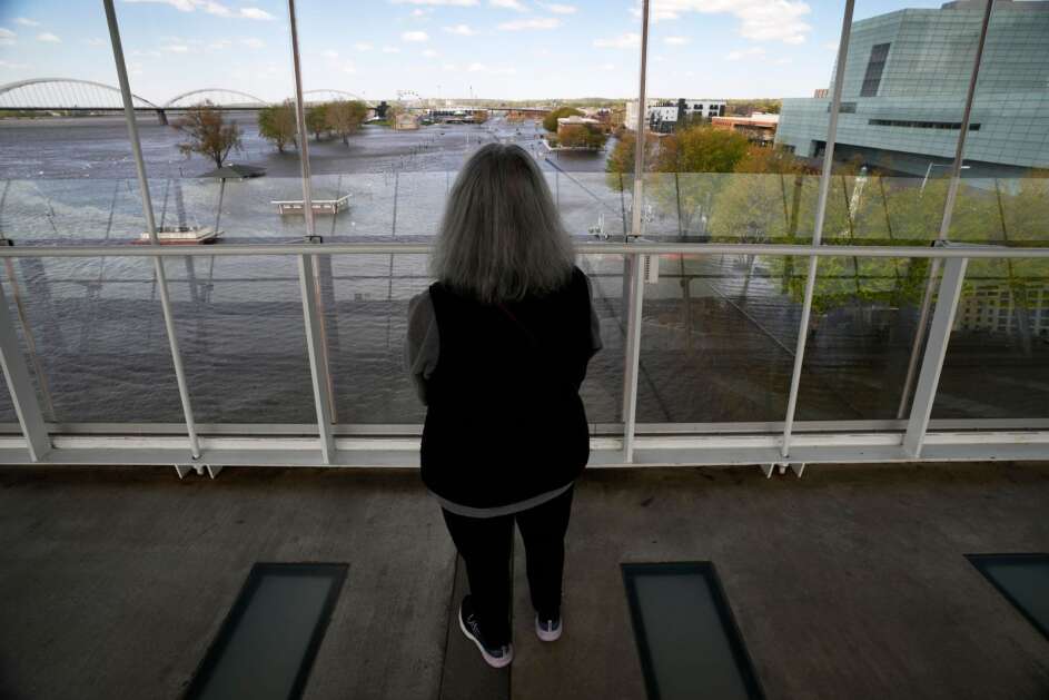Michelle Javornik, of Davenport, looks out at floodwaters Monday from the Mississippi River in Davenport. The rising Mississippi River is testing flood defenses as it crests, driven by a spring surge of water from melting snow. (AP Photo/Charlie Neibergall)