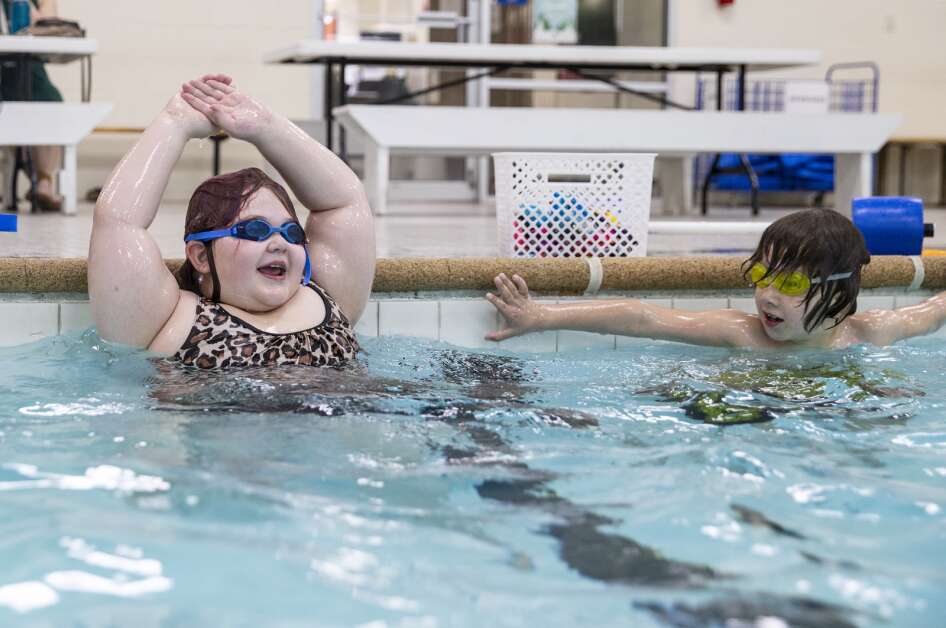 Second grader Samuel Majovic, right, watches his classmate, Delilah Meyer, practice “ice cream cone arms” to learn how to swim during an April 11 lesson at Bender Pool in Cedar Rapids. (Savannah Blake/The Gazette)