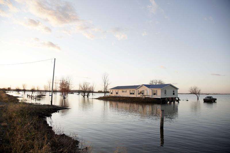 In this Oct. 22, 2019 photo, a home is surrounded by flood waters in Bartlett, Iowa. Iowans have suffered from increasingly severe weather events due to climate change. (AP Photo/Nati Harnik File)