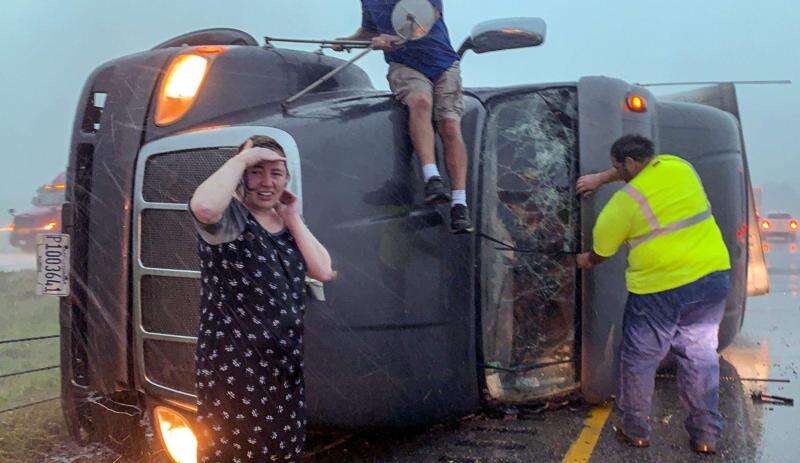 Passing drivers stop to help the driver of a tractor trailer after it overturned on Interstate 380 near 76th Avenue SW in Cedar Rapids on Aug. 10, 2020, during a derecho. (The Gazette)