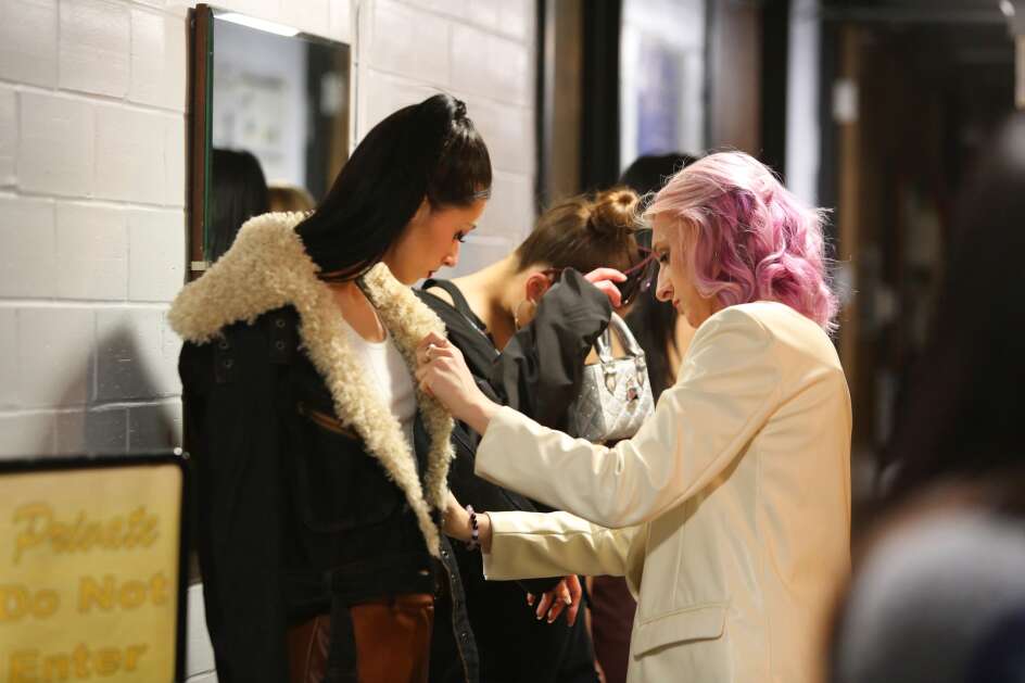 Steve Madden Associate Designer Kathryn Kaalberg lint-rolls a jacket worn by Olivia Mertes during intermission April 15 of The Fashion Show at Stephens Auditorium in Ames. (Bailey Cichon/The Gazette)