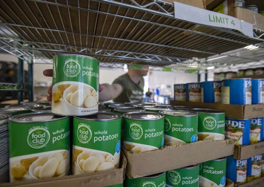 Food bank employee Ryan Hansen reaches for a can of potatoes while organizing shelves May 16 at the CommUnity Food Bank in Iowa City. The food back has served about 5,300 households so far in 2023 -- up from about 3,500 households in the same period last year. (Savannah Blake/The Gazette)