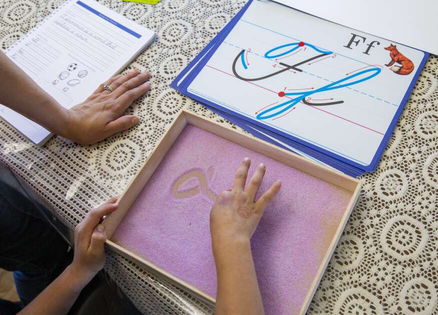 Gabriella Rustebakke watches as her son, Paul, age 7, practices writing his letters in cursive during an April 13 home schooling lesson at their home in Cedar Rapids. (Savannah Blake/The Gazette)