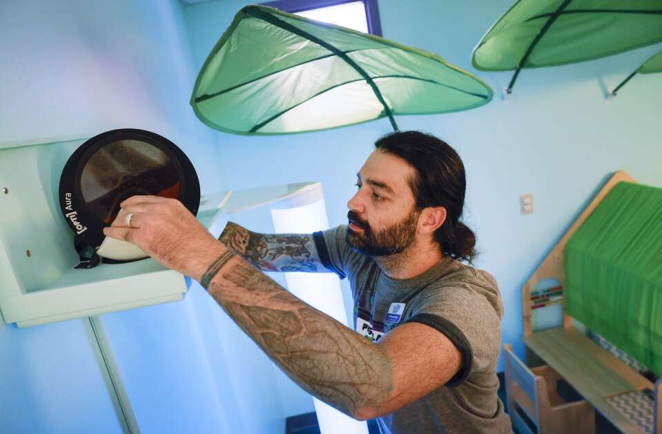 Exhibit/design manager Will Kemple-Taylor adjusts an aura LED projector in the Family Sanctuary at the Iowa Children's Museum at Coral Ridge Mall in Coralville, Iowa, on Thursday, May 11, 2023. The sensory room offers a quiet place for children who might be overstimulated or need a sensory-friendly environment away from the excitement of the other museum exhibits. The room has subdued lighting, books, seating, a playhouse with a ruffled roof, tactile blocks and an aura LED projector.  (Jim Slosiarek/The Gazette)