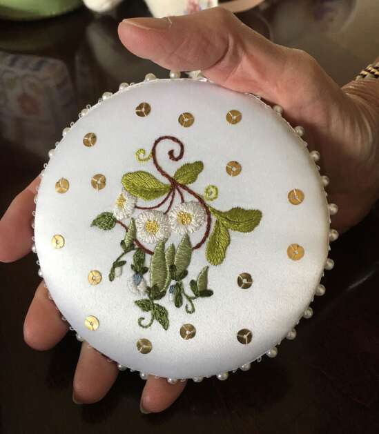 Needle artist Sheri Ekstrom of Cedar Rapids holds this pin cushion in the palm of her hand. It's reminiscent of the Victorian era, when women would tie a pin cushion to a belt under their skirt, to always have pins nearby. (Diana Nollen/The Gazette)